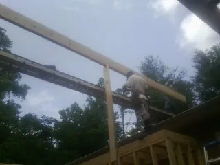 Carpenter setting a ridge beam over a new addition frame — Ice Dam Removal by Roofing Brothers in Erick