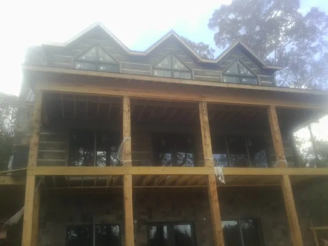 Dormers and porch framing on a large log home under construction — Roof Coating work by our crew in Erick