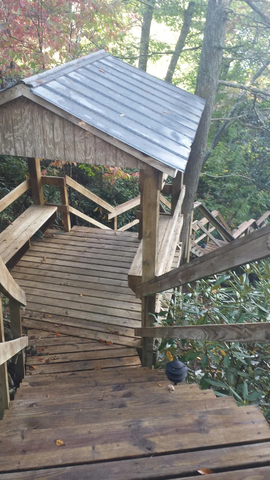 Metal roofed shelter over wooden steps on a wooded walkway — Skylight Repair & Installation work by our crew in Erick