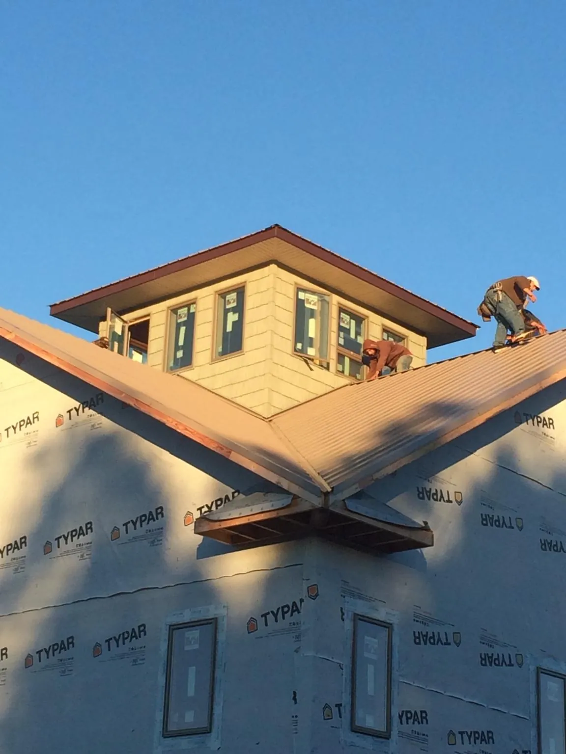 Roofers working around a rooftop cupola on a new metal roof at sunset — Roof Waterproofing in Erick by Roofing Brothers